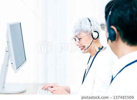 一位戴著耳機的老婦人正在操作電腦。 137485509