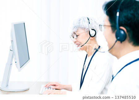 一位戴著耳機的老婦人正在操作電腦。 137485510