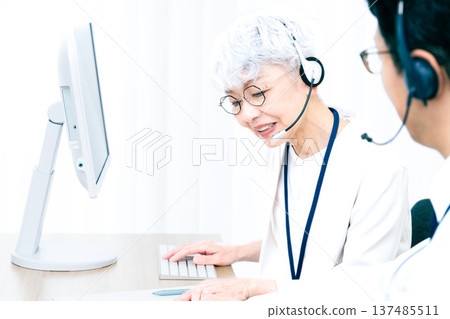 一位戴著耳機的老婦人正在操作電腦。 137485511