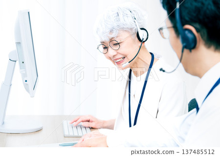 一位戴著耳機的老婦人正在操作電腦。 137485512