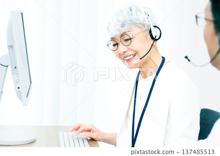 一位戴著耳機的老婦人正在操作電腦。 137485513