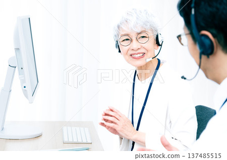 一位戴著耳機的老婦人正在操作電腦。 137485515