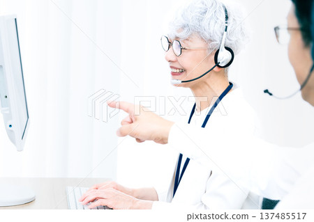 一位戴著耳機的老婦人正在操作電腦。 137485517