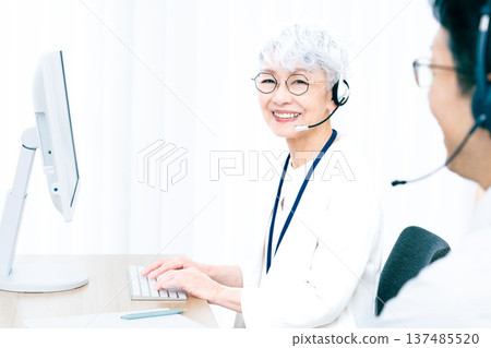 一位戴著耳機的老婦人正在操作電腦。 137485520