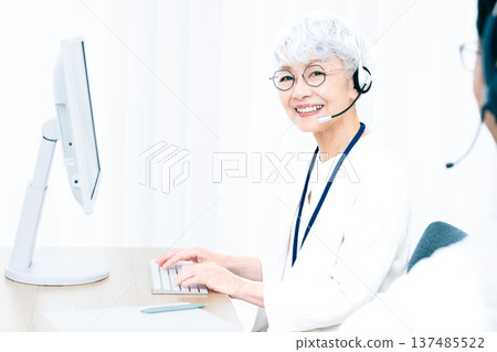 一位戴著耳機的老婦人正在操作電腦。 137485522