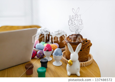A festive scene with traditional Easter cakes, colorful painted eggs, and small paint pots, suggesting a creative holiday preparation 137486572