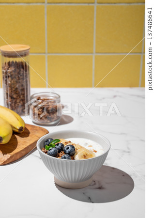 Natural greek yogurt with granola, blueberry and banana in a bowl on a marble table Natural greek yogurt with granola, blueberry and banana in a bowl on a marble table 137486641