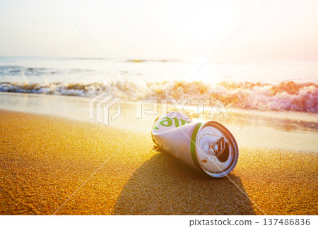 Crumpled beer can on sand beach at sea. Discarded broken beer can at seashore.  137486836