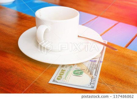 Coffee cup on cafe table with hundred dollars bill. Payment coffee drink on breakfast. 137486862