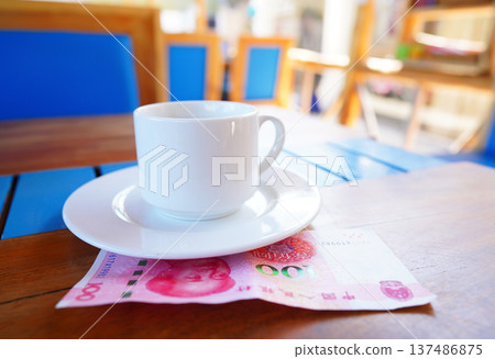 Coffee cup on table with hundred yuan bill in cafe. Payment coffee drink on breakfast.  137486875