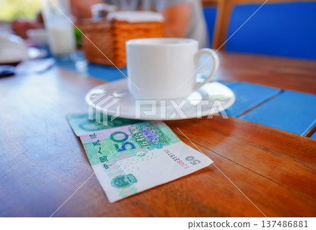 Coffee cup on table with fifty yuan bill in cafe. Payment coffee drink on breakfast. Coffee cup on table with fifty yuan bill in cafe. Payment coffee drink on breakfast. 137486881