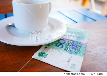 Coffee cup on table with fifty yuan bill in cafe. Payment coffee drink on breakfast.  137486883