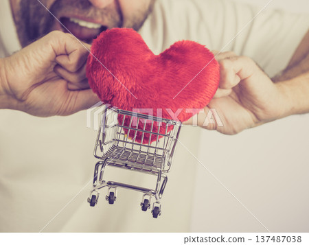 Man holds shopping cart with heart. Man holds shopping cart with heart. 137487038