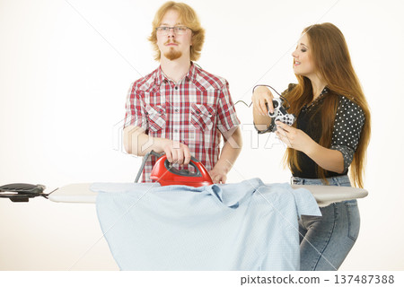 Woman controling man to do ironing Woman controling man to do ironing 137487388