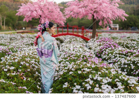 woman in yukata (kimono dress) with sakura flower or cherry blossom blooming in garden woman in yukata (kimono dress) with sakura flower or cherry blossom blooming in garden 137487600