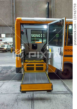 View of lowered wheelchair lift on public school bus city street View of lowered wheelchair lift on public school bus city street 137487759