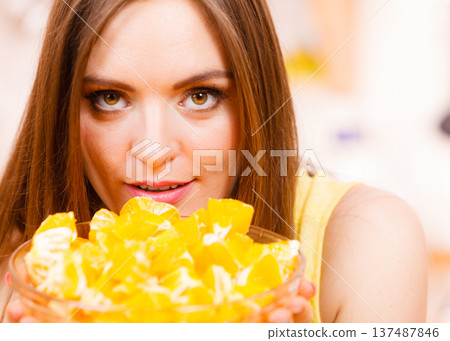 Woman holds bowl full of sliced orange fruits 137487846