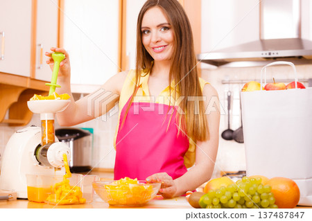 Woman making orange juice in juicer machine 137487847