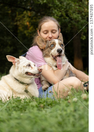 Professional dog walker young woman with pack of dogs is sitting on grass and enjoying walk animals. Professional dog walker young woman with pack of dogs is sitting on grass and enjoying walk animals. 137487895