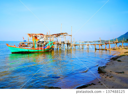 Fishing boat at wooden pier on clear blue sky, calm ocean water in daytime in coastal. Fishing boat 137488125