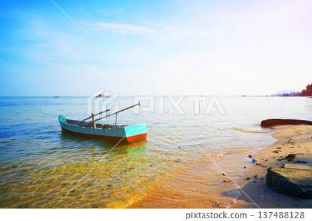 Boat on shore at beach during late afternoon with clear sky and calm water in background. Boat on shore at beach during late afternoon with clear sky and calm water in background. 137488128