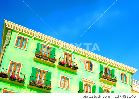 Green facade building with balconies and palm tree on blue sky background. Apartment buildings Green facade building with balconies and palm tree on blue sky background. Apartment buildings 137488140
