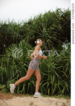 Active Woman Running. Athletic Woman Sporting Headphones And Zebra Attire Enjoying Bright Trail Run Active Woman Running. Athletic Woman Sporting Headphones And Zebra Attire Enjoying Bright Trail Run 137488329