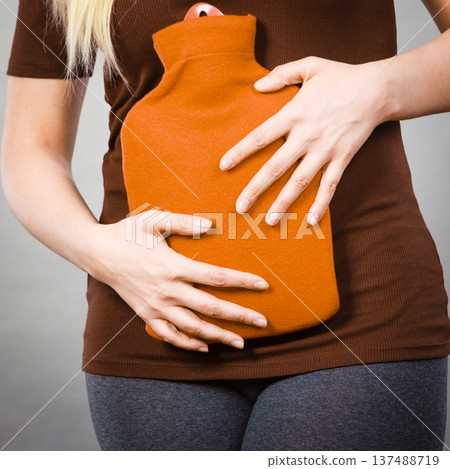 Girl having stomach ache, holding hot water bottle 137488719