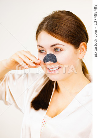 Woman applying pore strips on nose Woman applying pore strips on nose 137489498