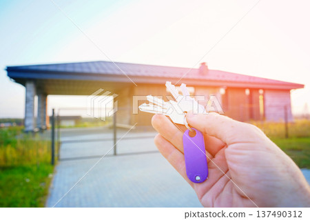 Keys to new house. Keys against of new house facade. Buying new suburb home, villa rent. 137490312