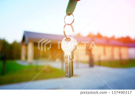 Keys to new house. Keys against of new house facade. Buying new suburb home, villa rent. 137490317