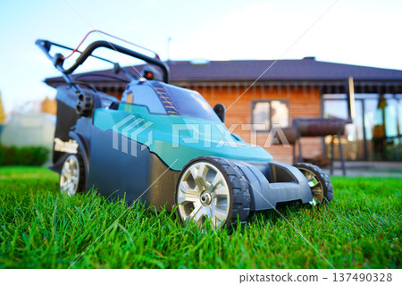 Lawn Mower Electric for cutting grass in garden. Mowing Grass use Lawn Mower in yard. Lawn Mower Electric for cutting grass in garden. Mowing Grass use Lawn Mower in yard. 137490328