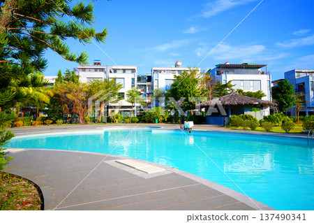 Swimming pool with turquoise water surrounded by dreamy beach hotel buildings 137490341