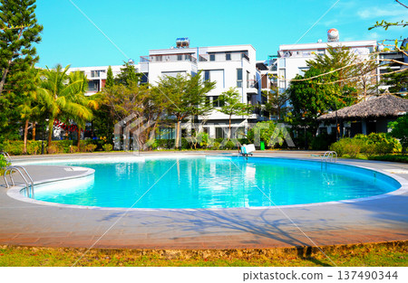 Swimming pool with turquoise water surrounded by dreamy beach hotel buildings Swimming pool with turquoise water surrounded by dreamy beach hotel buildings 137490344