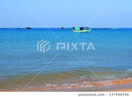 Fishing boat in sea on blue sky. View on ocean from beach. Fishing boats in sea along shore. Fishing boat in sea on blue sky. View on ocean from beach. Fishing boats in sea along shore. 137490346