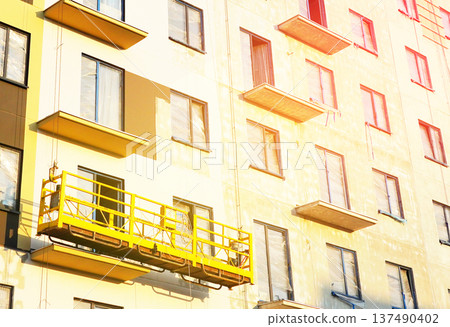 Suspended construction cradle on painting facade of building. Mobile scaffolding platform  137490402