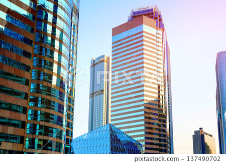 Skyscrapers in bright glass exteriors sunlight on sunset. Modern facade office buildings Skyscrapers in bright glass exteriors sunlight on sunset. Modern facade office buildings 137490702