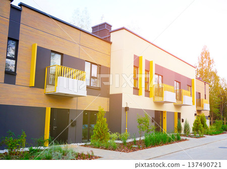 Modern townhome Exterior With Green Accents, Sunlight in Serene Neighborhood Setting. 137490721