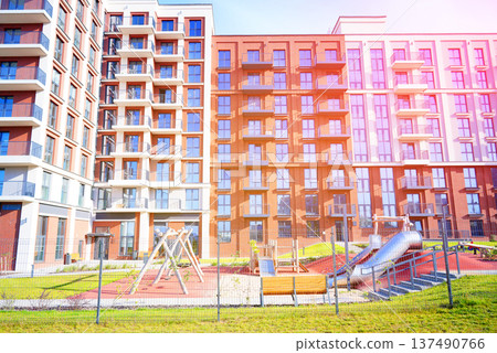 Facade building. Block house with playground in closed courtyard. Cityscape of residential area Facade building. Block house with playground in closed courtyard. Cityscape of residential area 137490766