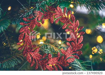 Decorative red wreath on a Christmas tree with bokeh lights. Decorative red wreath on a Christmas tree with bokeh lights. 137490920