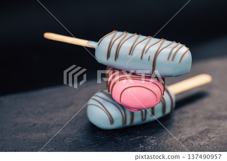 Dessert in the form of popsicle ice cream covered with pink and blue chocolate. 137490957