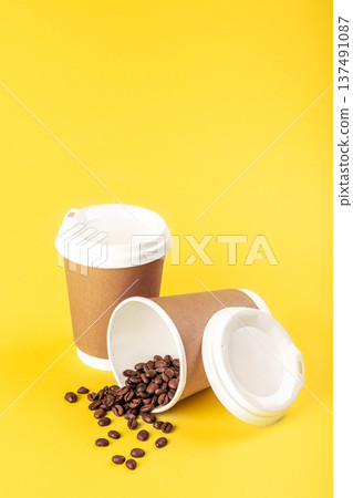 Disposable cups and scattered coffee beans on a yellow background isolated. 137491087
