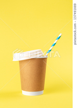 Disposable cup with a straw on a yellow background isolated. Disposable cup with a straw on a yellow background isolated. 137491089