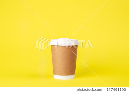 Disposable paper cup on a yellow background isolated. 137491100