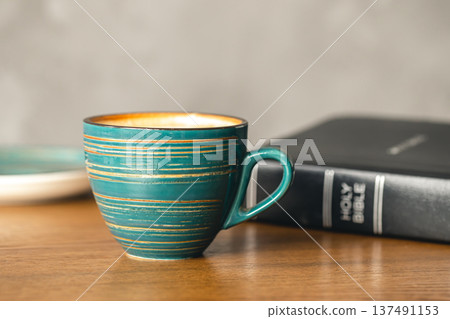 A cup of coffee and a Bible on a wooden table, close-up. 137491153