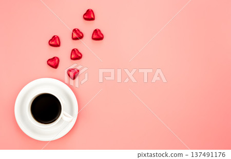 Cup of coffee and heart shaped sweets on a pink background, flat lay. 137491176