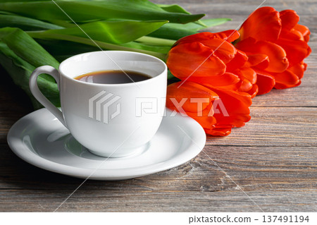 Cup of coffee and red tulips on a wooden surface. Cup of coffee and red tulips on a wooden surface. 137491194