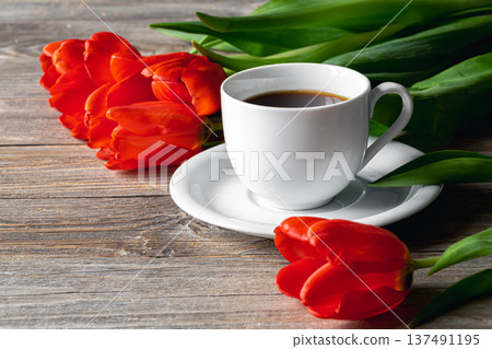 Cup of coffee and red tulips on a wooden surface. 137491195