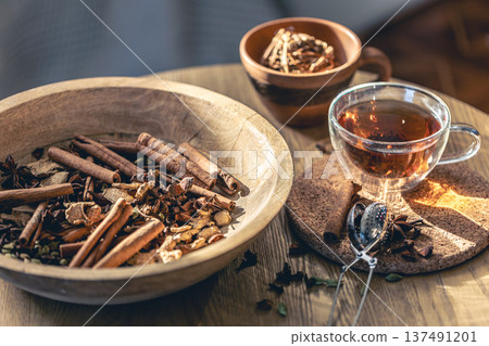 Cup of freshly brewed black tea, different types of spices on wooden table. 137491201