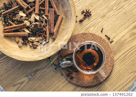Cup of freshly brewed black tea, different types of spices on wooden table. 137491202